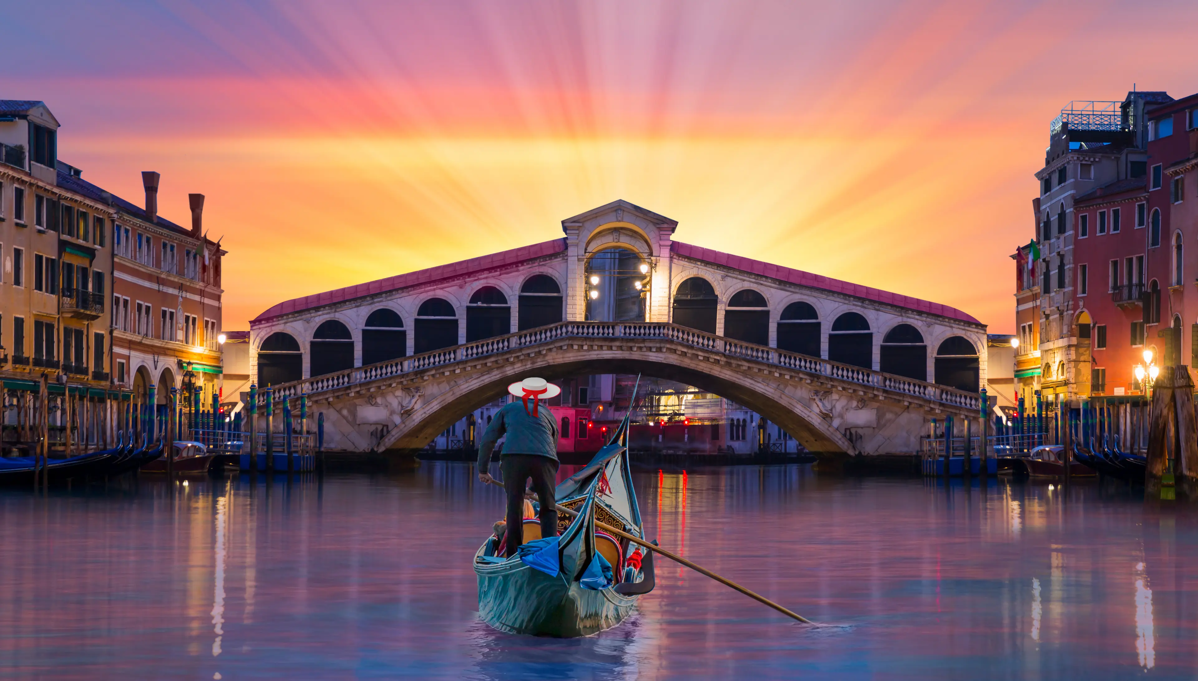 A gondolier approaching the Rialto bridge during sunset