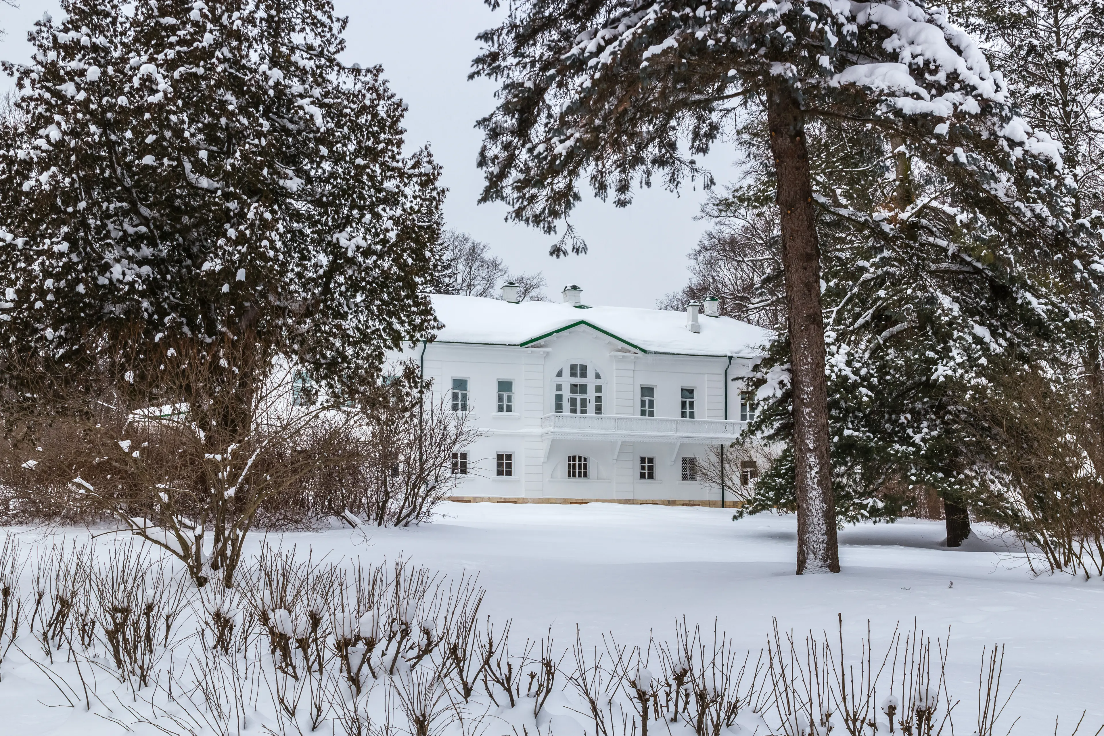 A big white house, in a snowy forested landscape