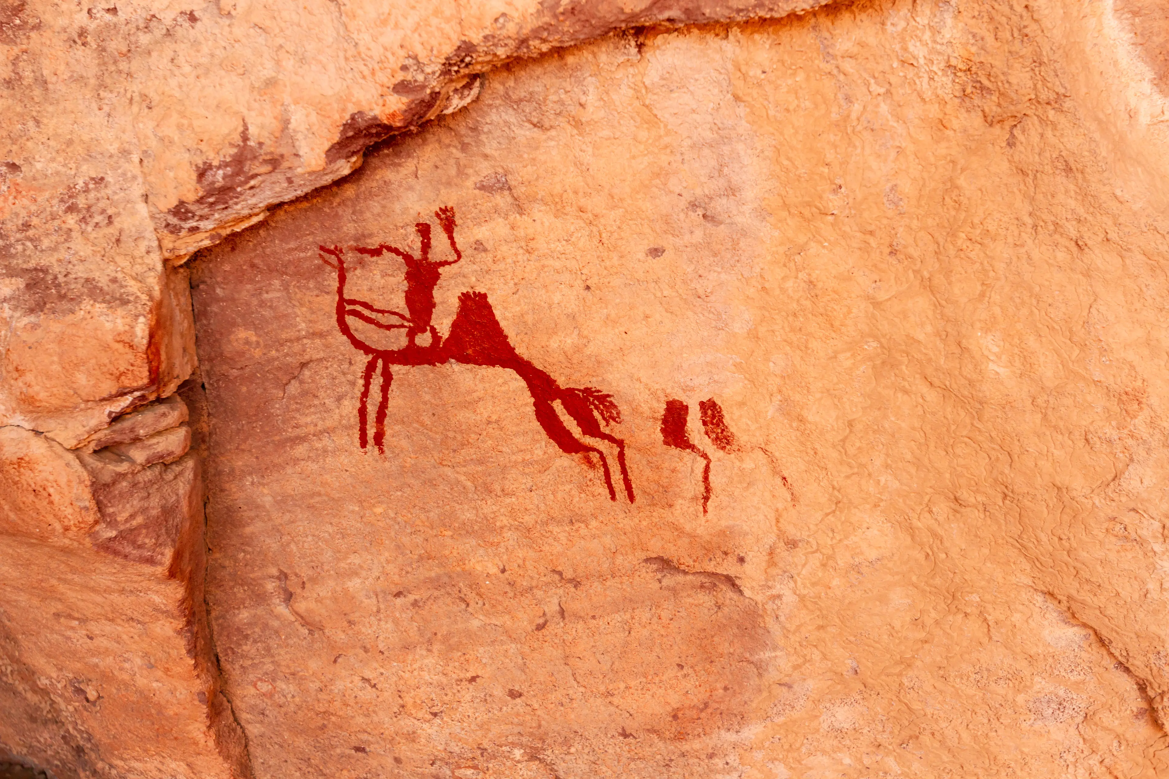 Neolithic rock art of a camel with rider. Tadrart Rouge.