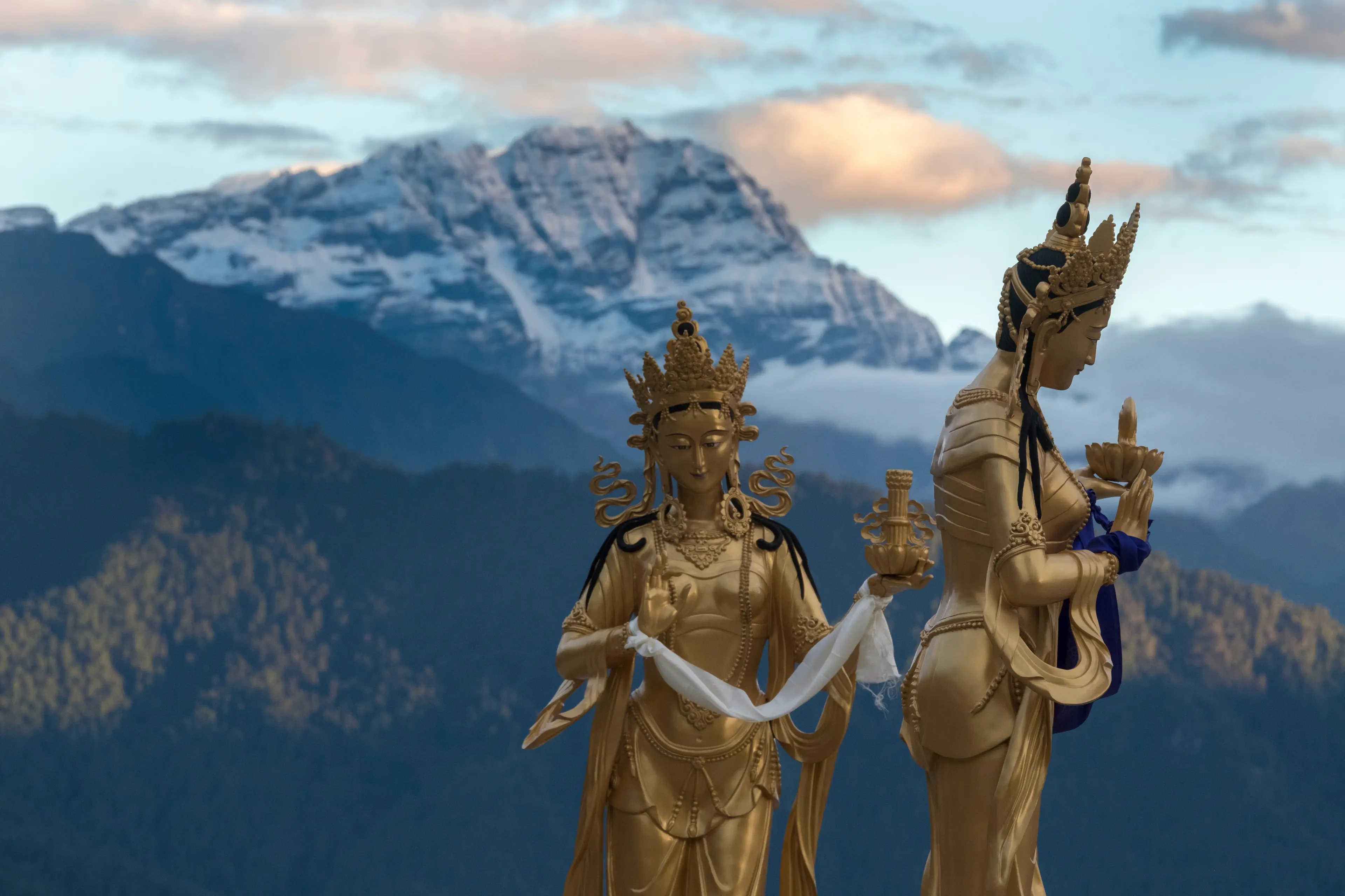 Statues of goddesses with Himalayan peaks in the background