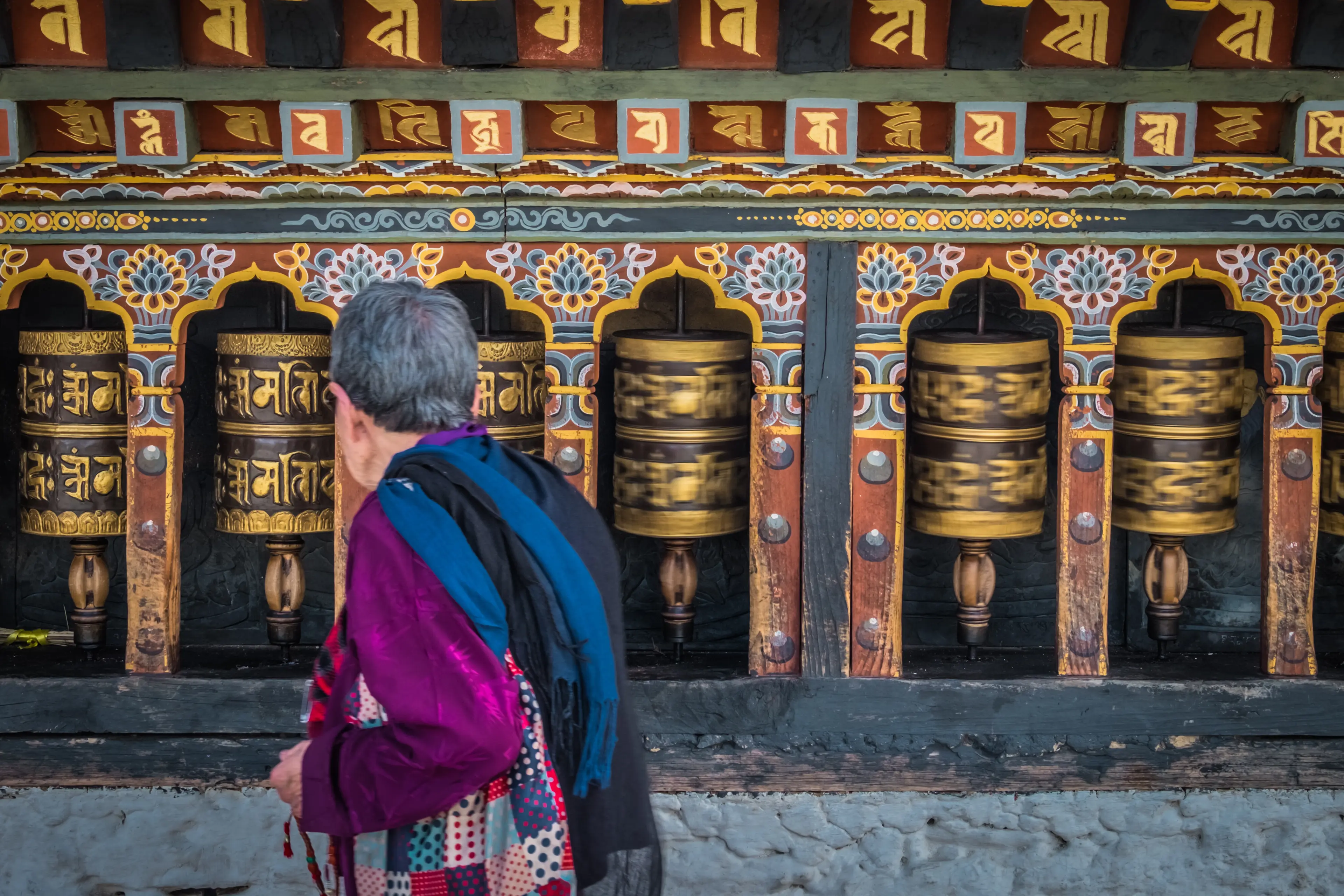 An old woman spinning prayer wheels in Thimphu
