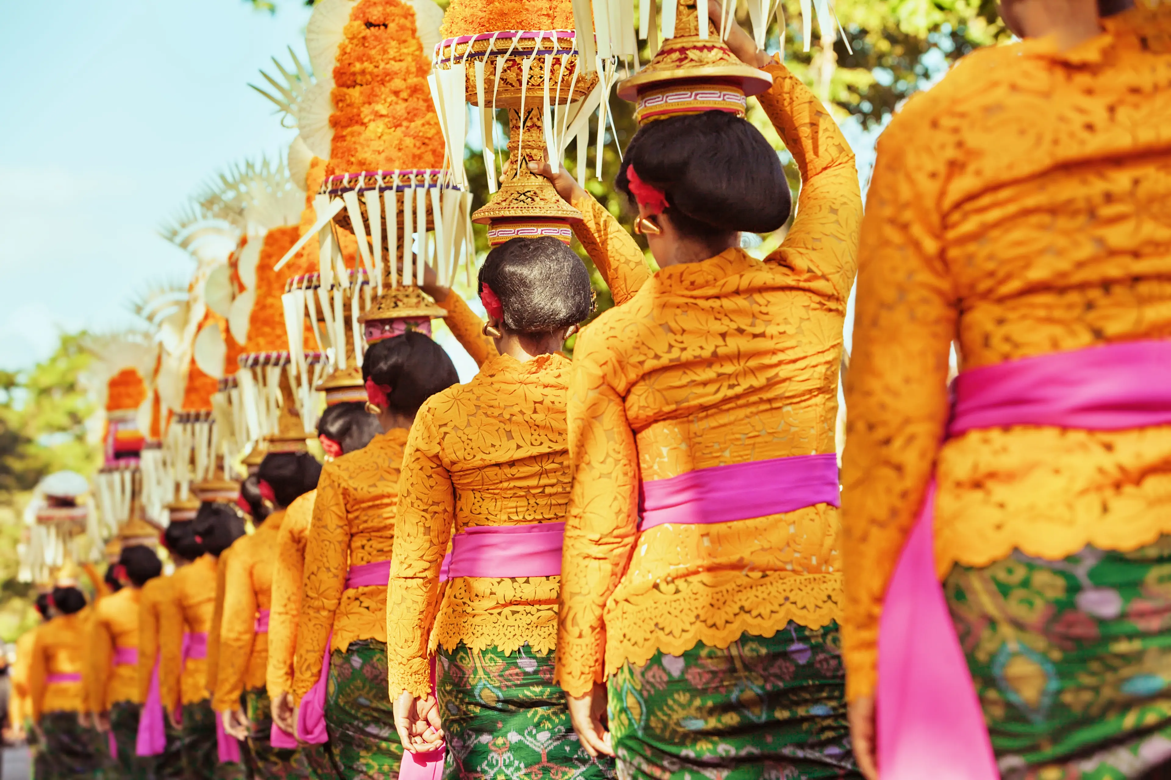 Balinese women in traditional costumes - sarong, carry offering on heads for Hindu ceremony
