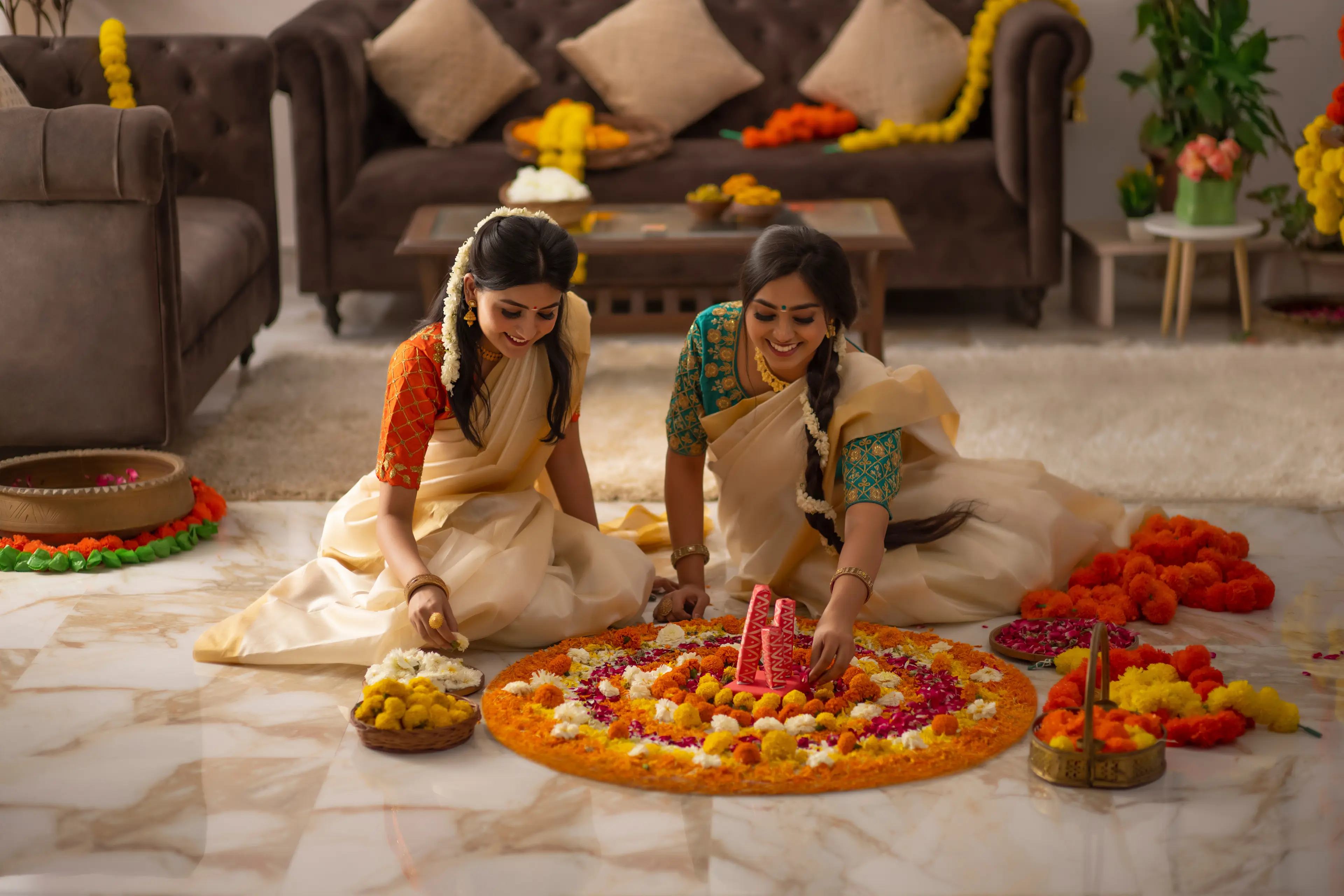 South Indian women in white saree decorating floor with flowers to celebrate Onam South Indian women in white saree decorating floor with flowers to celebrate Onam