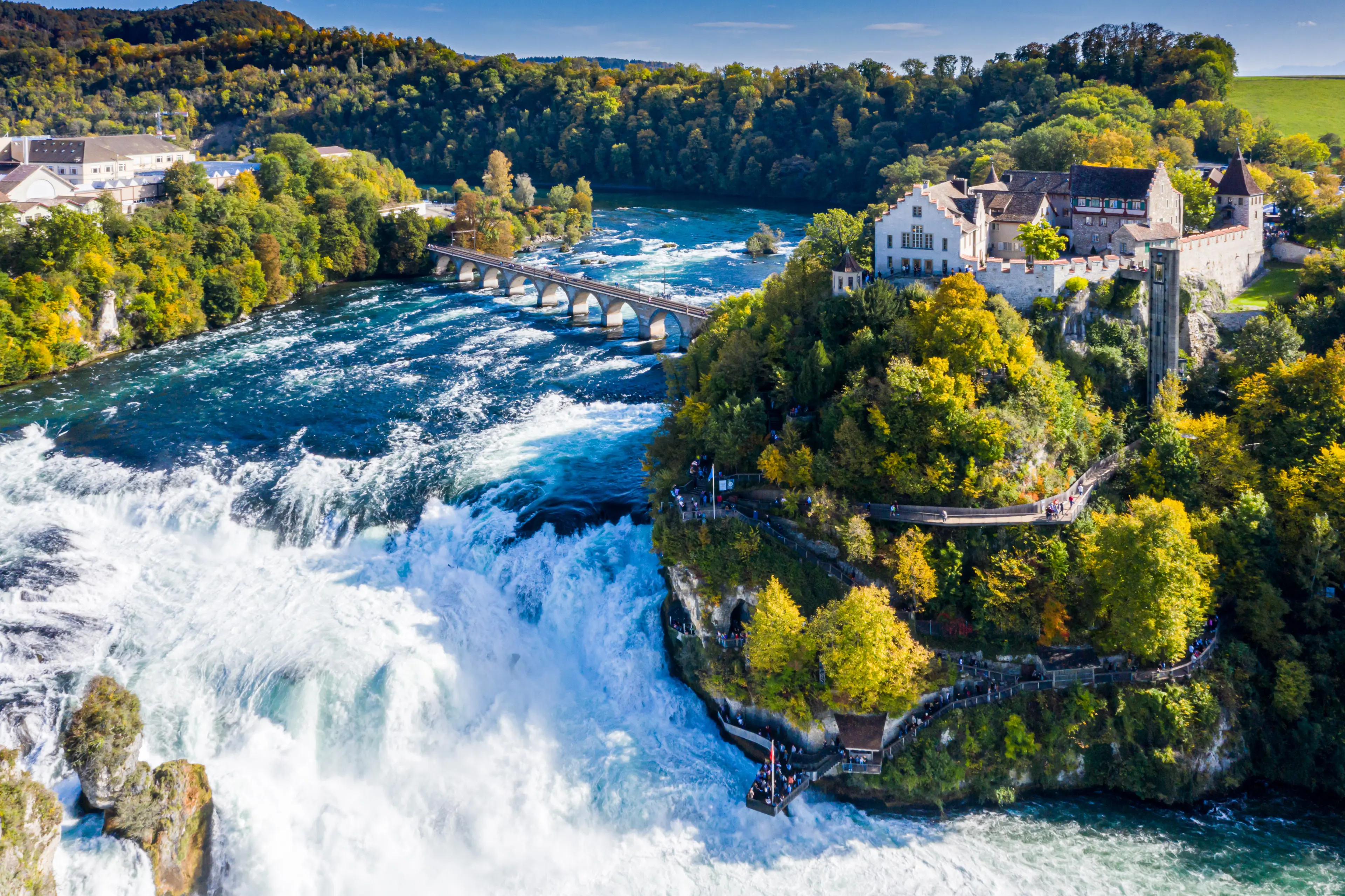 Rhine Falls with bridge and border between the cantons Schaffhausen and Zurich. Cliff-top Schloss Laufen castle, Laufen-Uhwiesen.