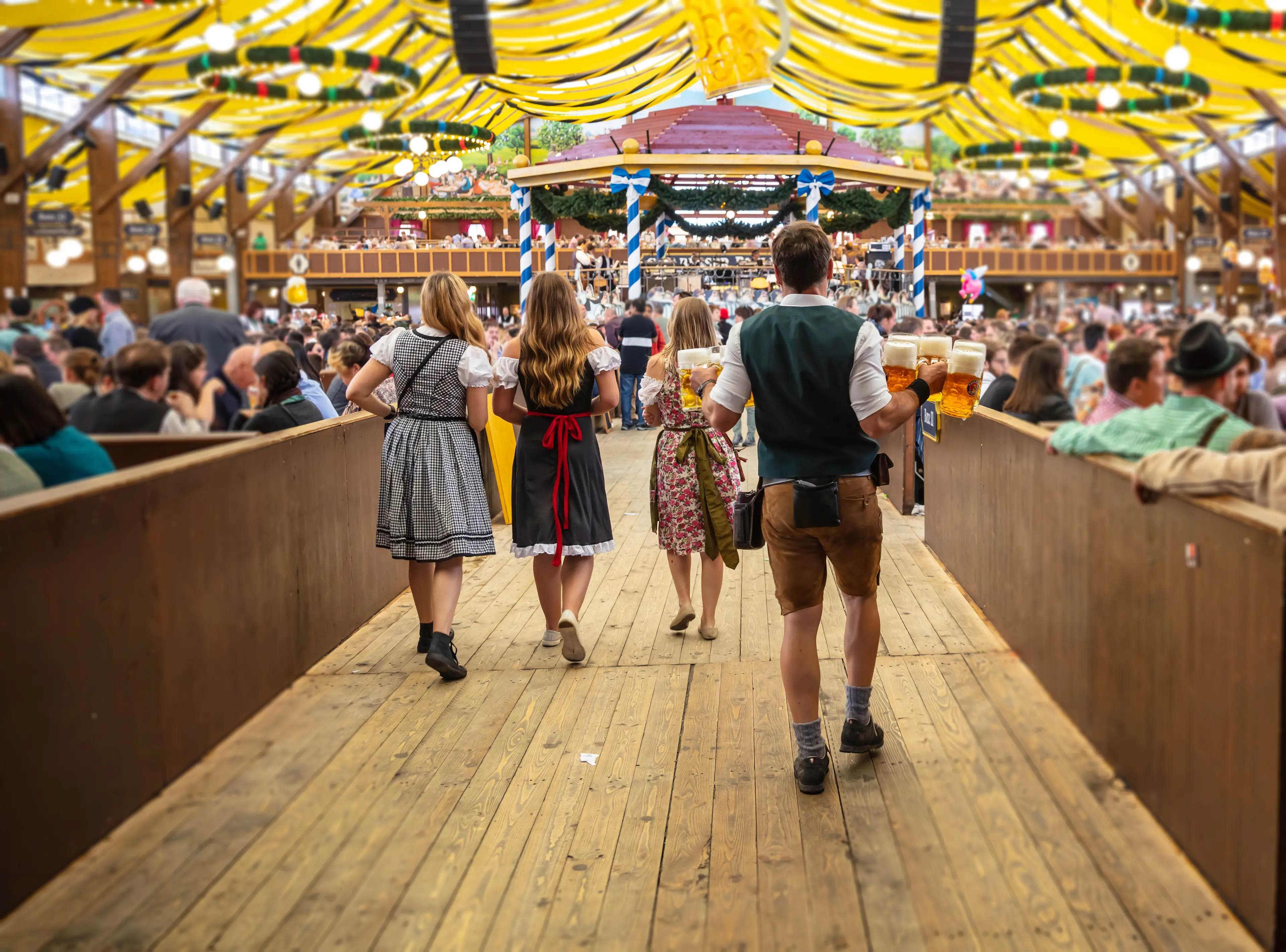 A waiter dressed in lederhosen carrying pints of beer at Oktoberfest