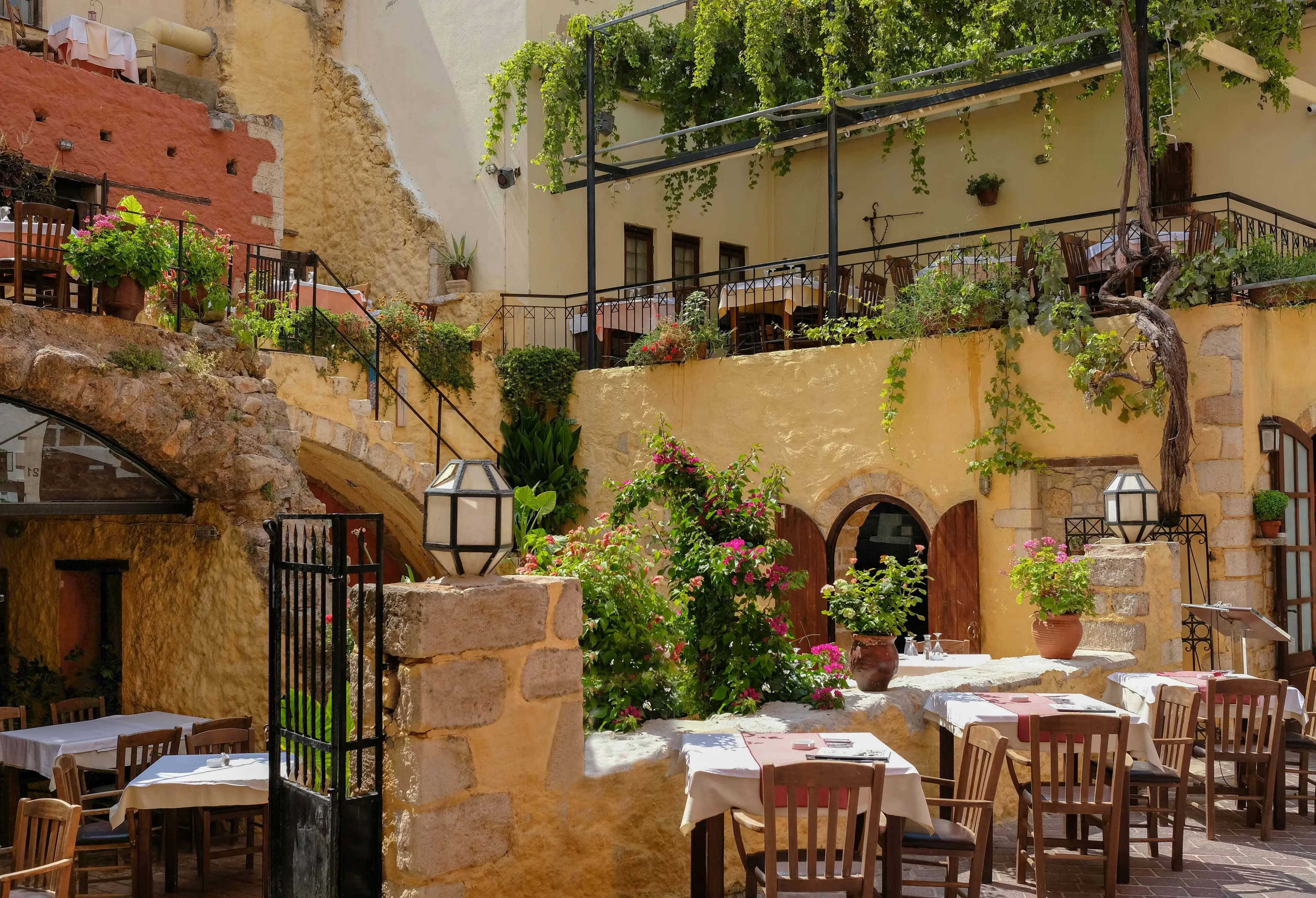Patio in a Greek tavern with arches, stairs, plants and lanterns