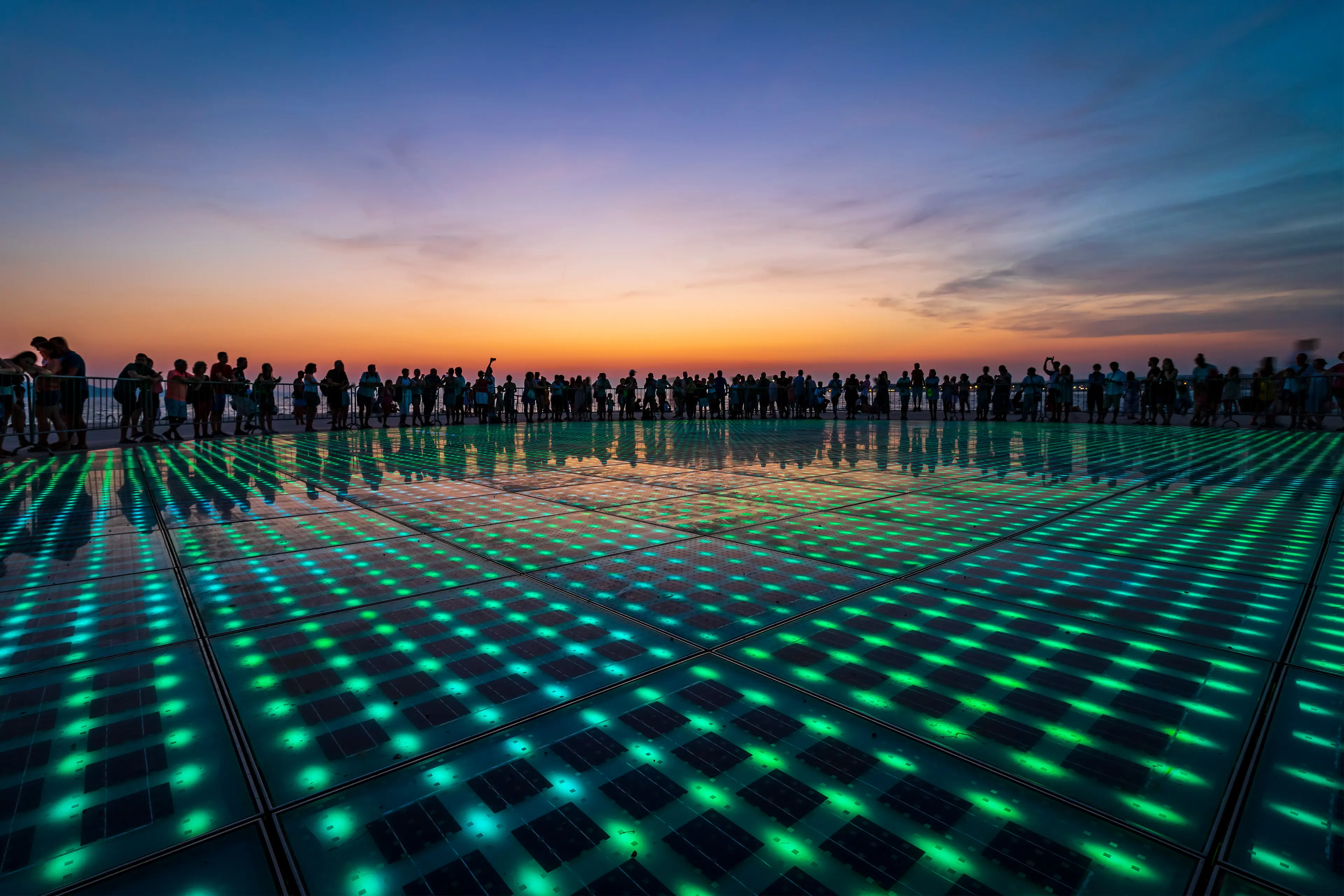 Human sihlouettes surrounding the light display of the monument to the sun