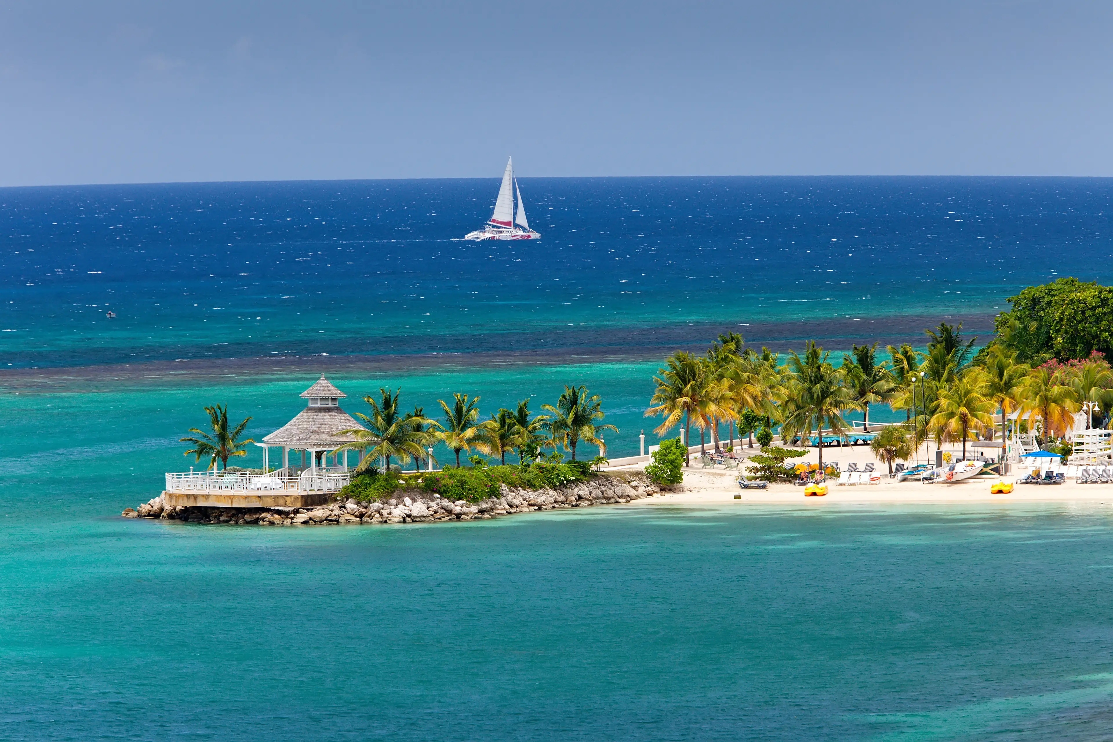 A small inlet with palm trees and a pavillion by the sea