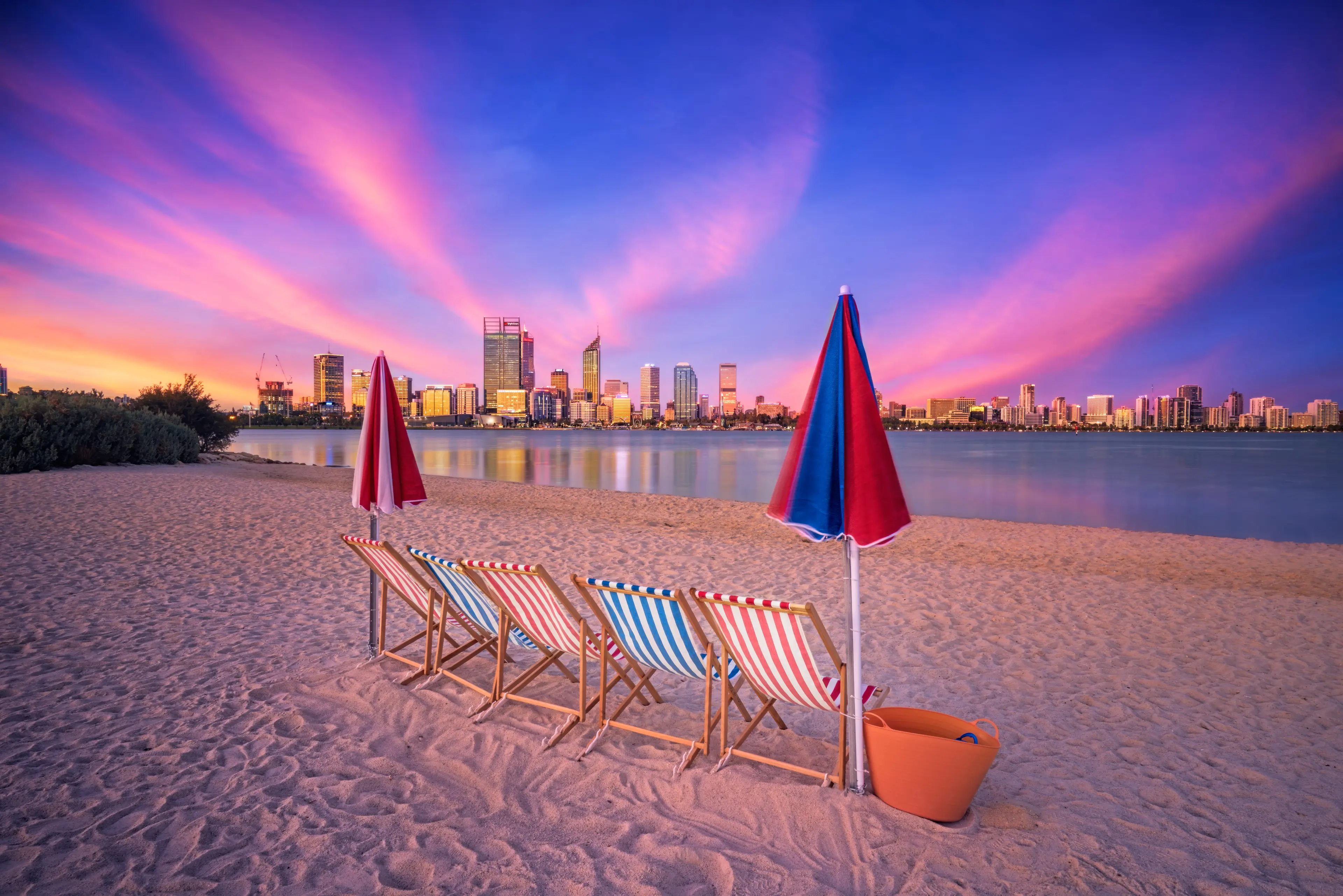 Deck chairs on a beach overlooking the city